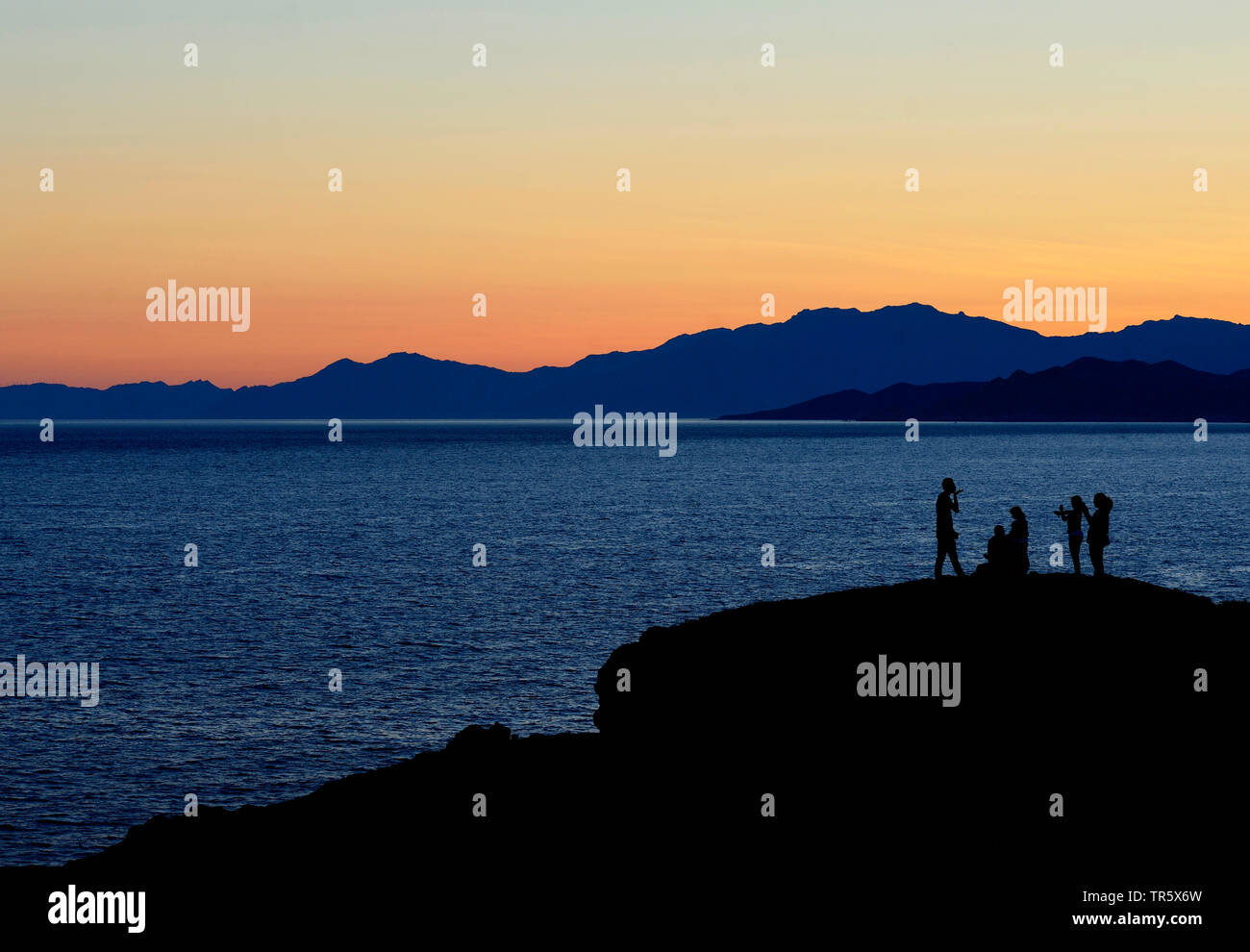 Personen, die auf einem Felsen an der Küste am Morgen in der Nähe von Ile Rousse im Norden der Insel Korsika, Frankreich, Korsika, Ile Rousse Stockfoto