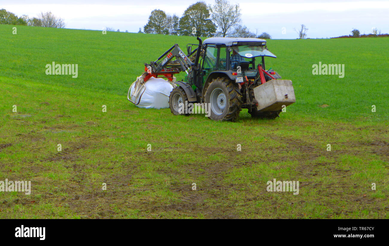 Traktor auf einer Wiese mit Silageballen, Deutschland Stockfoto