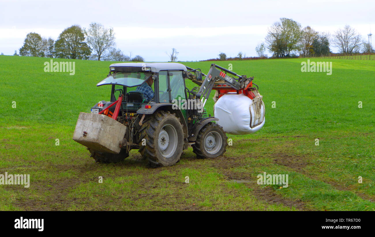 Traktor auf einer Wiese mit Silageballen, Deutschland Stockfoto