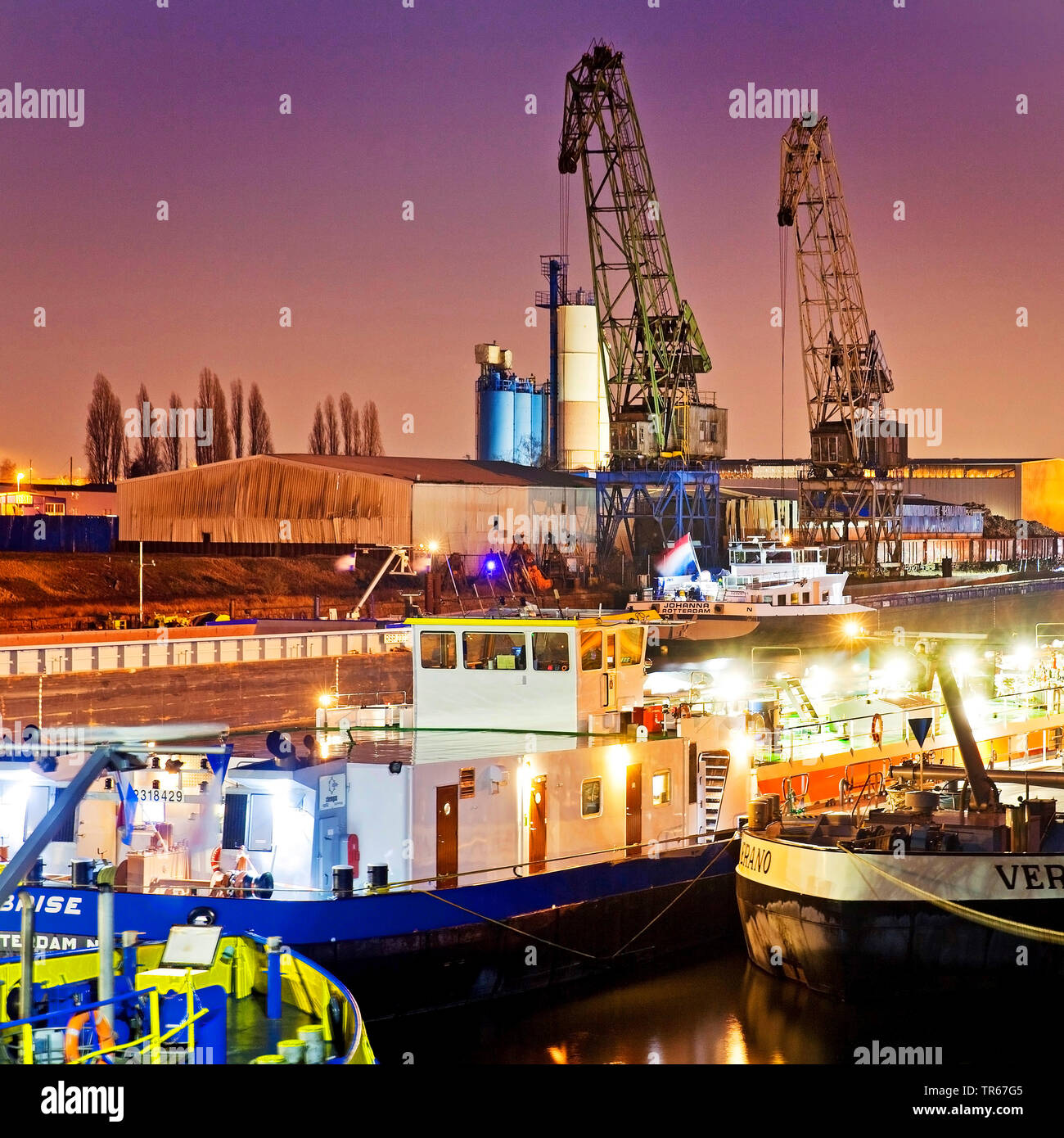 Frachtschiffe und Krane in den Binnenhafen Duisburg bei Nacht, Deutschland, Nordrhein-Westfalen, Ruhrgebiet, Duisburg Stockfoto