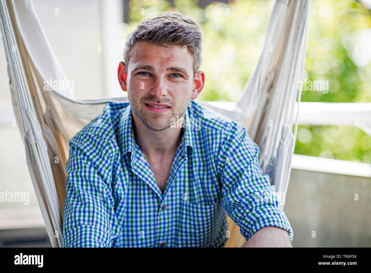 Junge Mann in einem hängenden Sitz sitzt, Deutschland Stockfoto