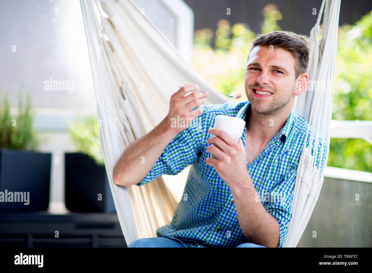 Genießen Sie einen Latte Macchiato in einem hammok im Garten, Deutschland Stockfoto