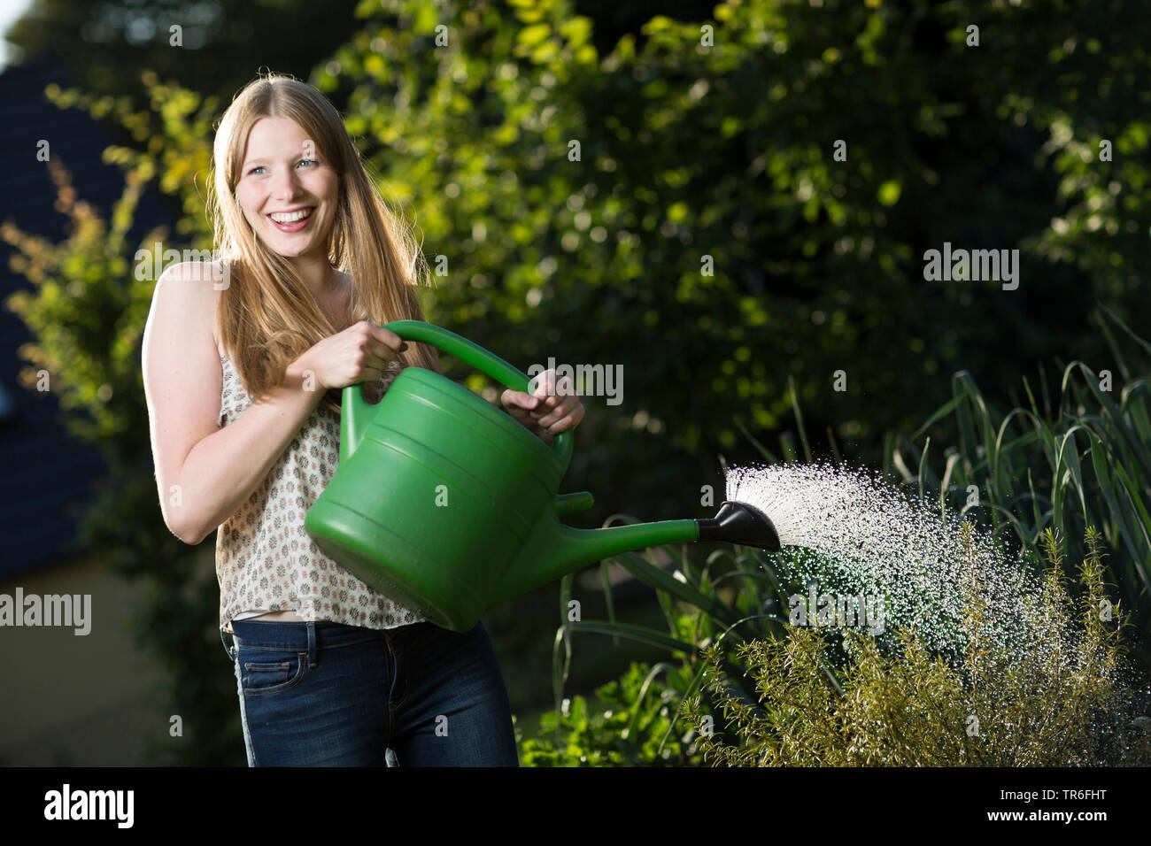 Junge Frau Bewässerung ein gemüsebeet mit Gießkanne, Deutschland Stockfoto