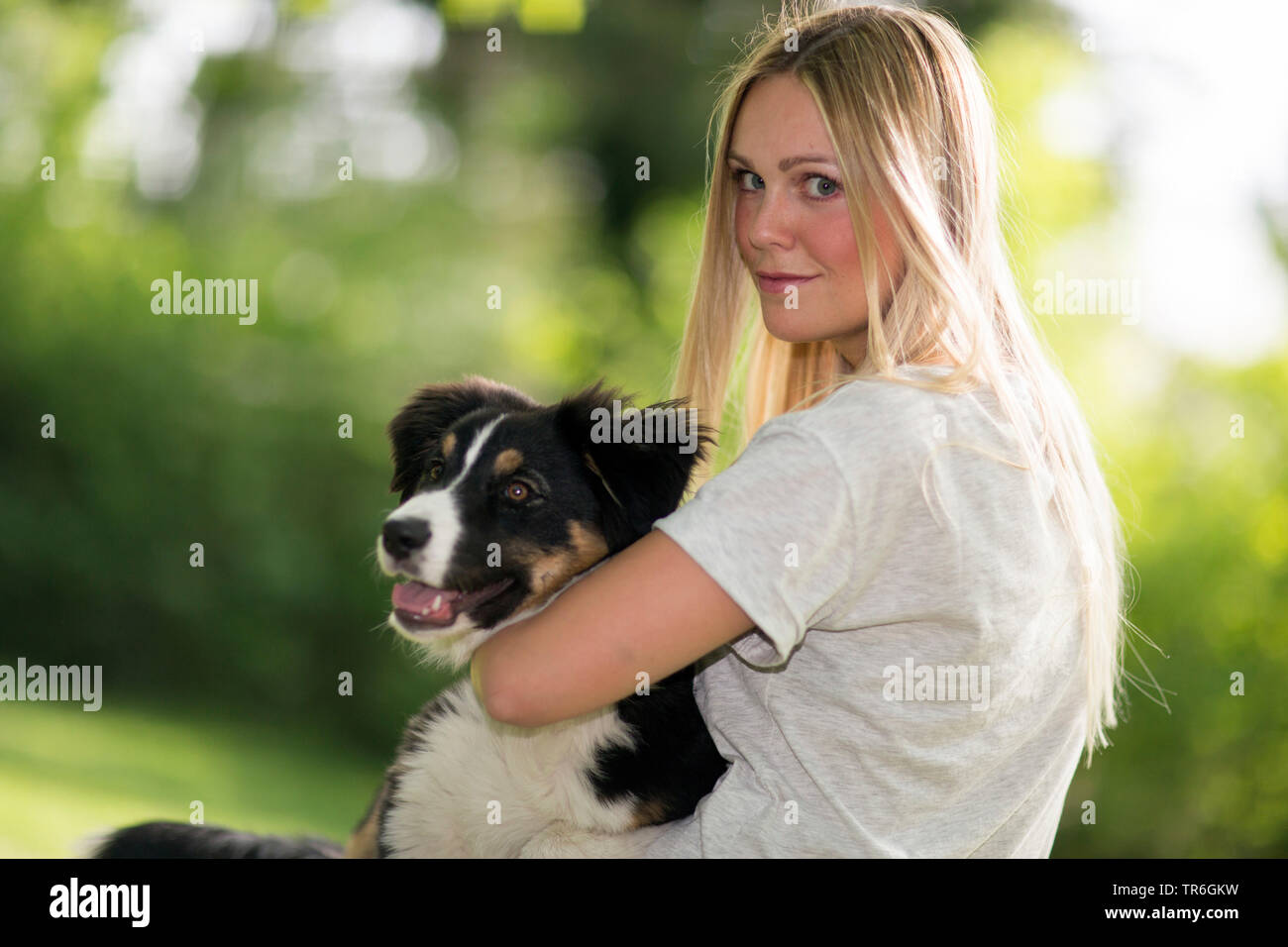 Australian Shepherd (Canis lupus f. familiaris), blonde Frau mit ein Welpe auf dem Schoß, Deutschland Stockfoto