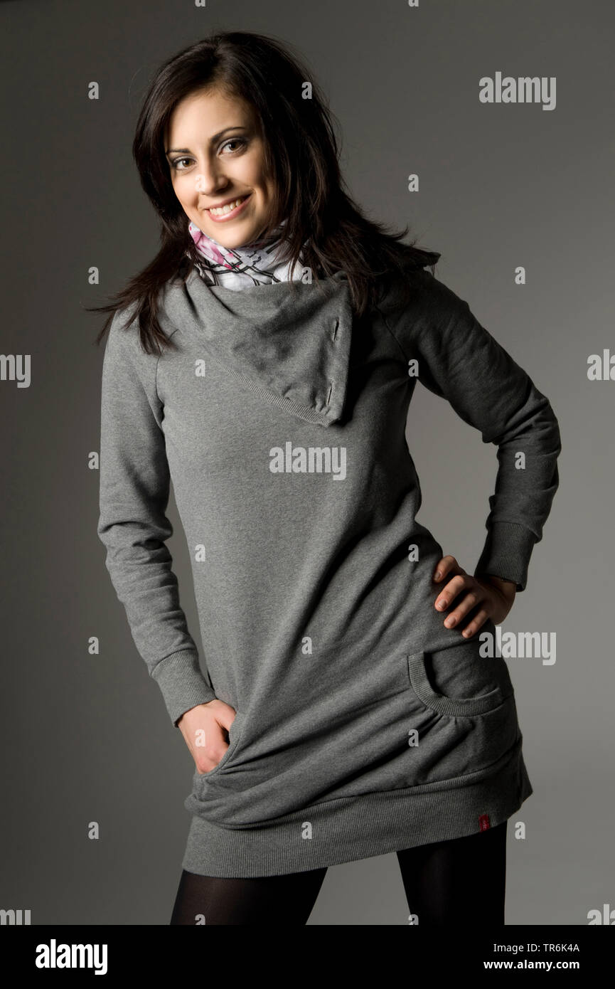 Junge, attraktive Frau in einem grauen pullover Posing Stockfoto