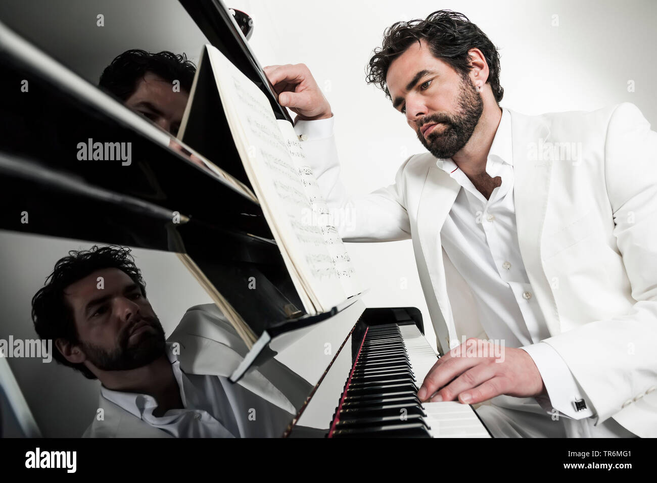 Junger Mann im weissen Anzug an einem Klavier, Deutschland Stockfoto