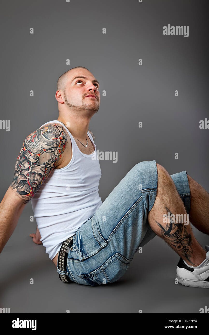 Jungen tätowierten Mann mit Glatze und Bart mit muscelshirt und Jeans, Deutschland Stockfoto