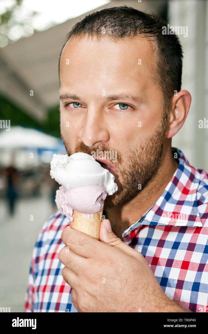 Stattlicher Mann mit Bart ein Eis essen, Deutschland Stockfoto