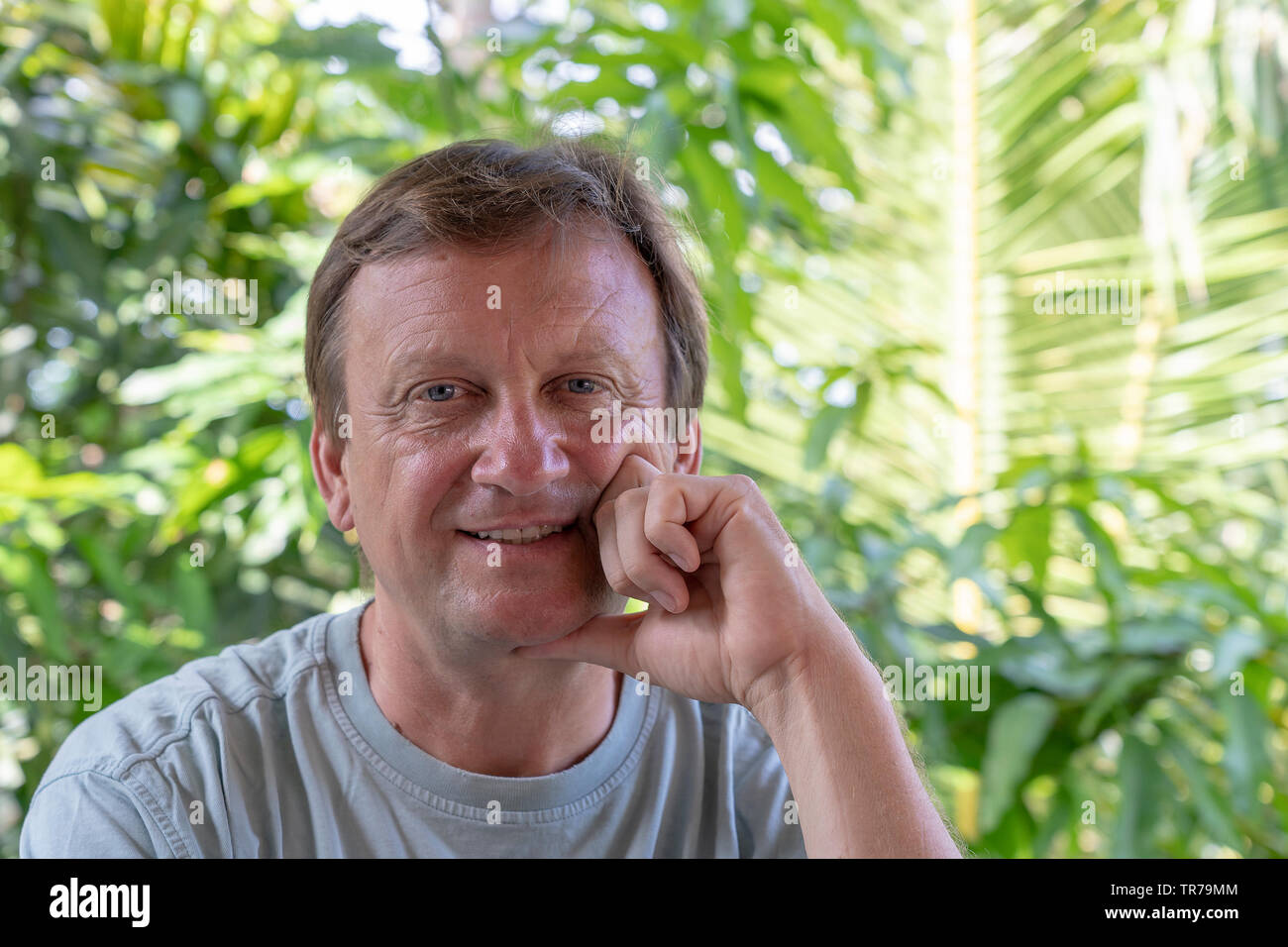 Porträt eines Mannes mittleren Alters, die auf dem Hintergrund der grüne Blätter in der Natur, in der Nähe Stockfoto