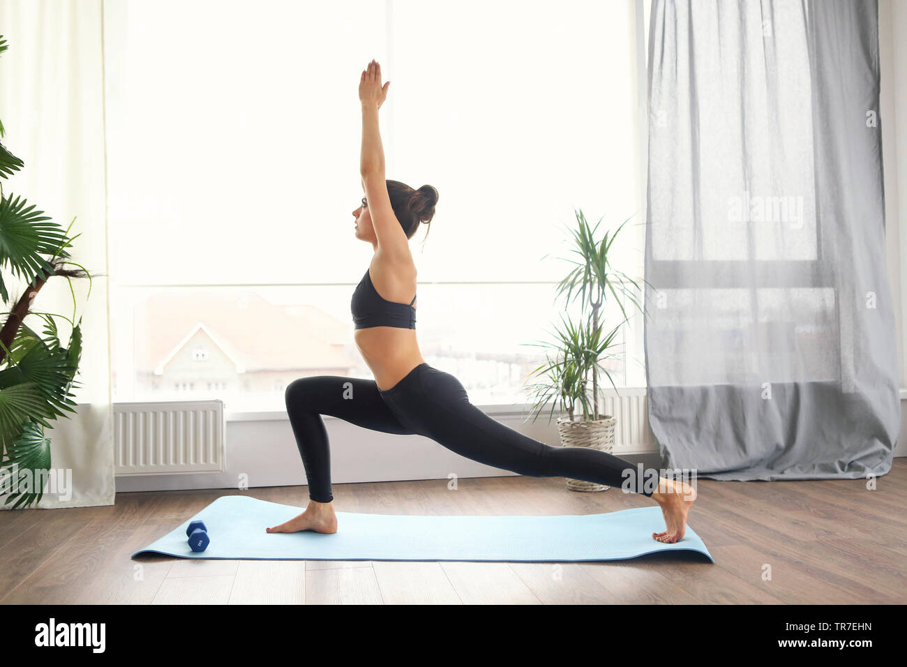 Lächelnde Frau in Sportkleidung Ausübung auf Fitness Matte und Kamera im Wohnzimmer Stockfoto