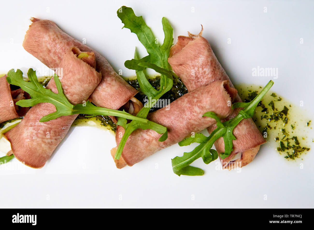 Gekochte Zunge mit Füllung und Sauce auf einem weißen Teller. Stockfoto