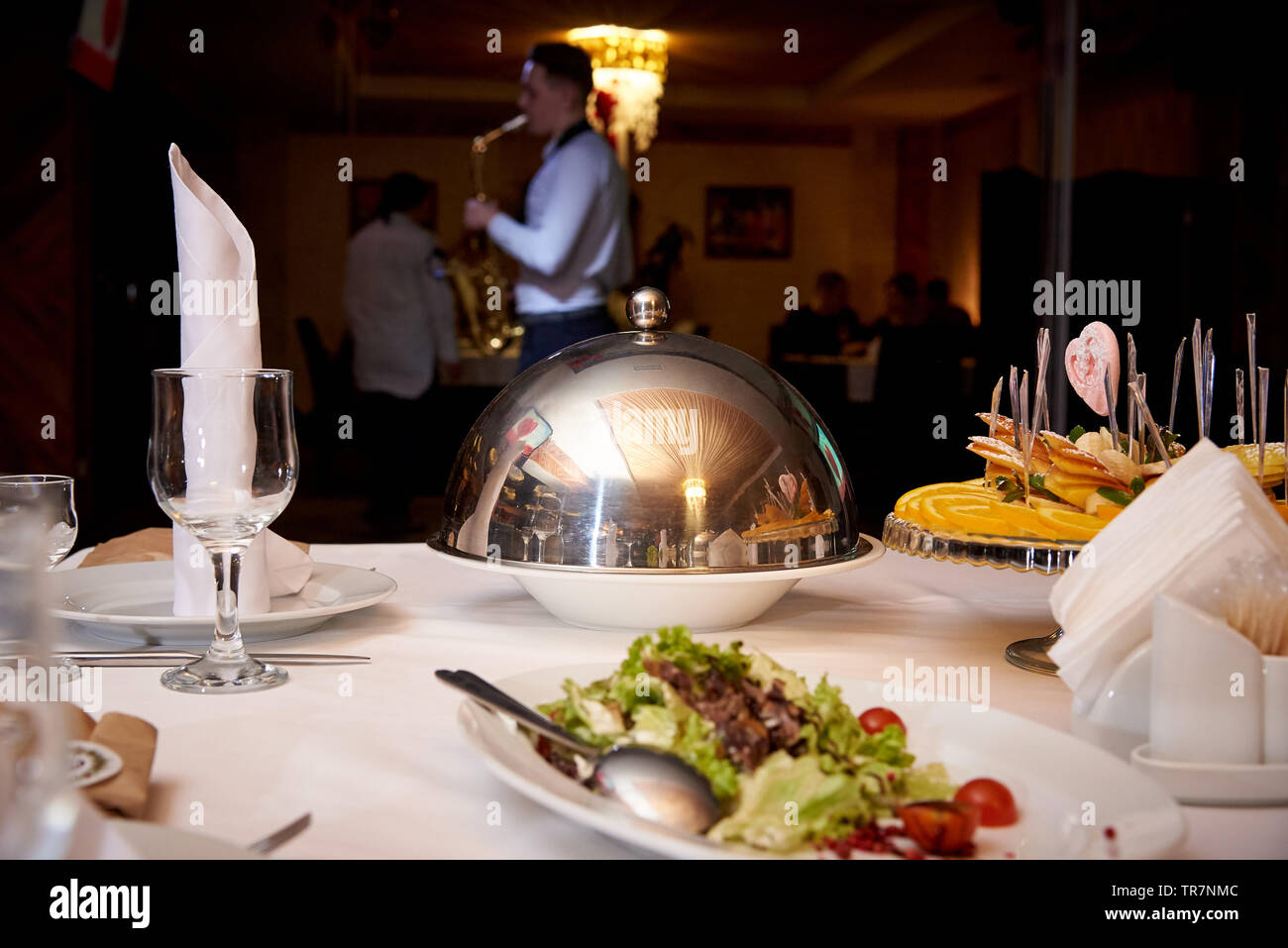 Abendessen serviert. Warme Speise auf der Kuppel Fach auf dem Server Tabelle auf einem unscharfen Hintergrund spielen saxophonist für Gäste. Stockfoto