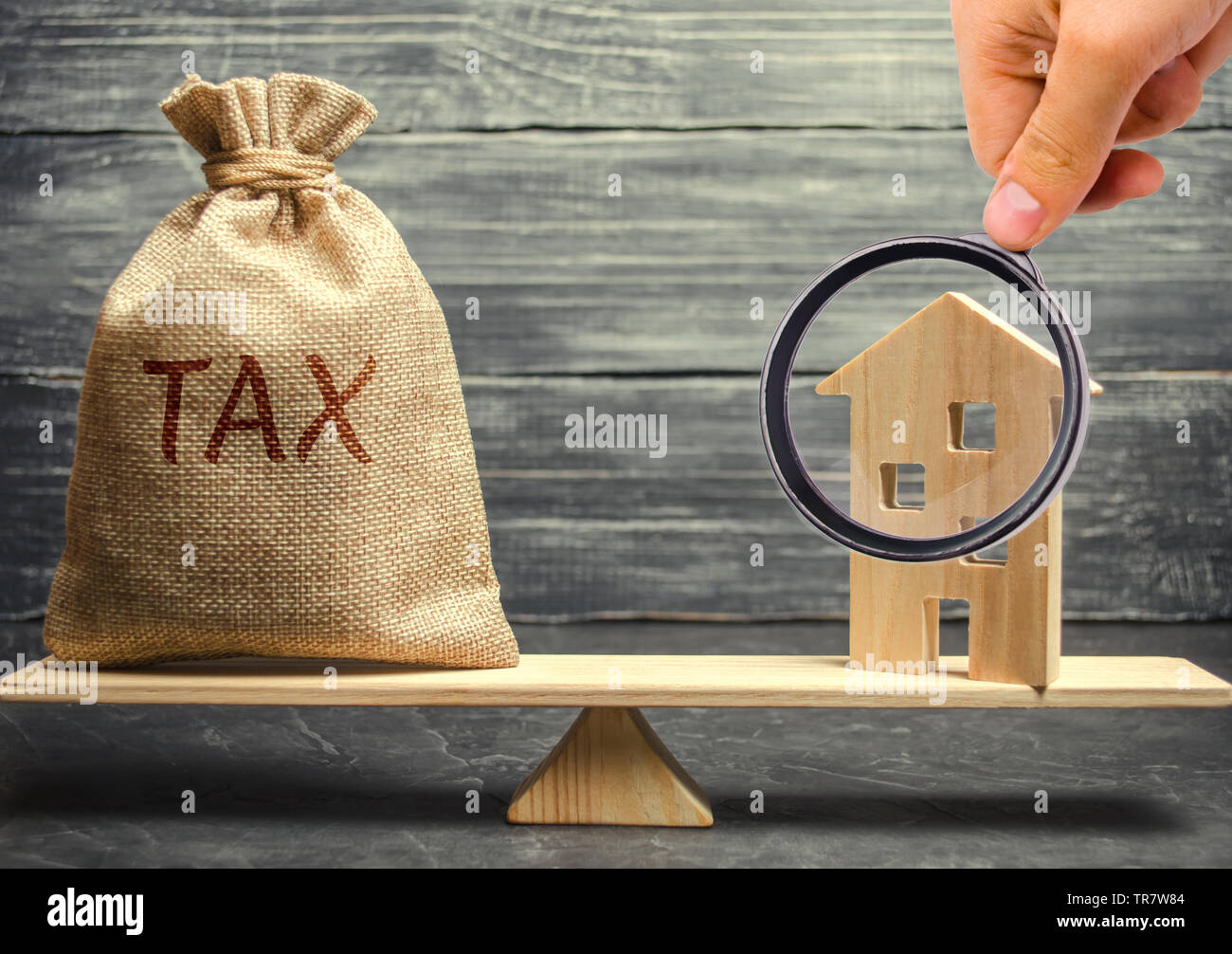 Holzhaus und ein Geld beutel mit dem Wort Steuer auf der Waage. Steuern auf Immobilien, Zahlung. Register der Steuerzahler für die Eigenschaft. Gesetzestreue Bürger. Stockfoto
