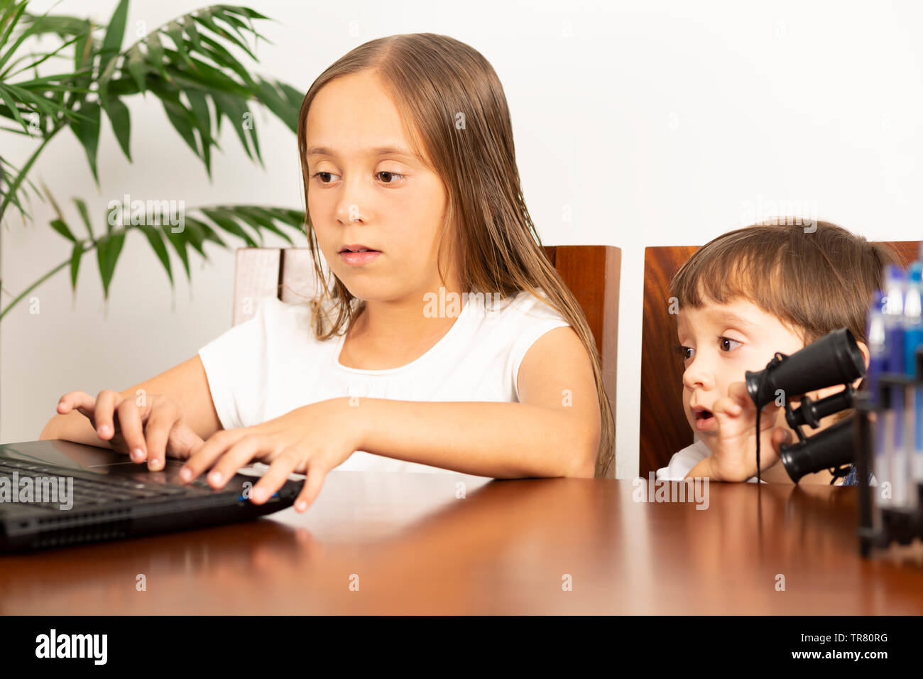 Glückliche Mädchen und Jungen an seinem Schreibtisch mit Laptop sitzen Stockfoto