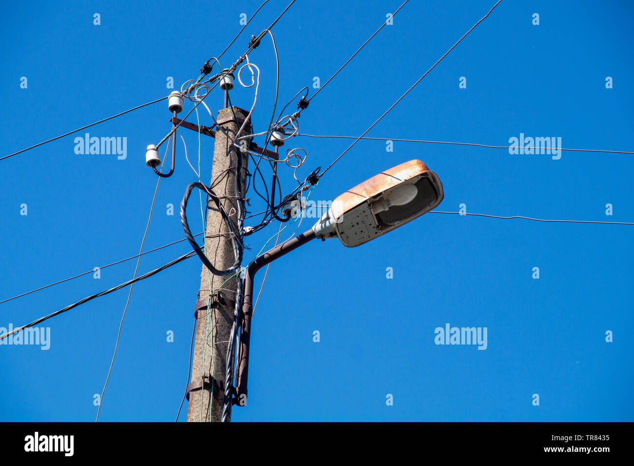 Straßenlaterne mit Drähten gegen den blauen Himmel Stockfoto
