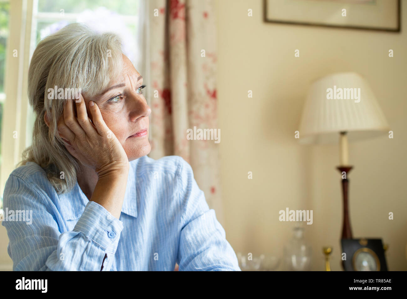 Ältere Frau Leiden mit Depression aus dem Fenster zu Hause Suchen Stockfoto