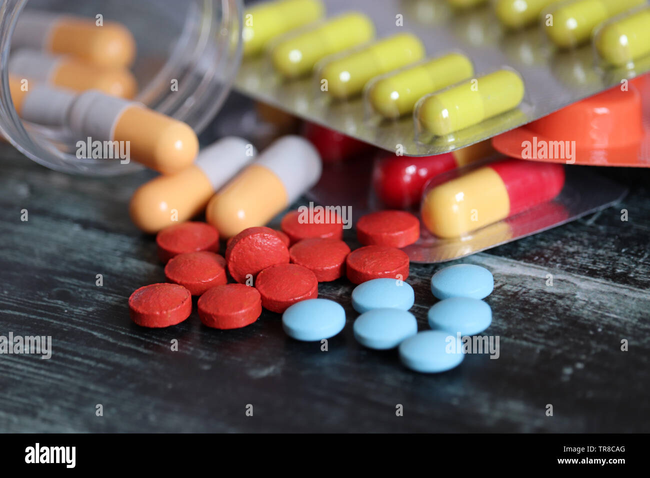 Pillen und Kapseln auf dunklen Holztisch, viele bunte Medikation close-up. Konzept der Apotheke, Vitamine, Gesundheit Stockfoto