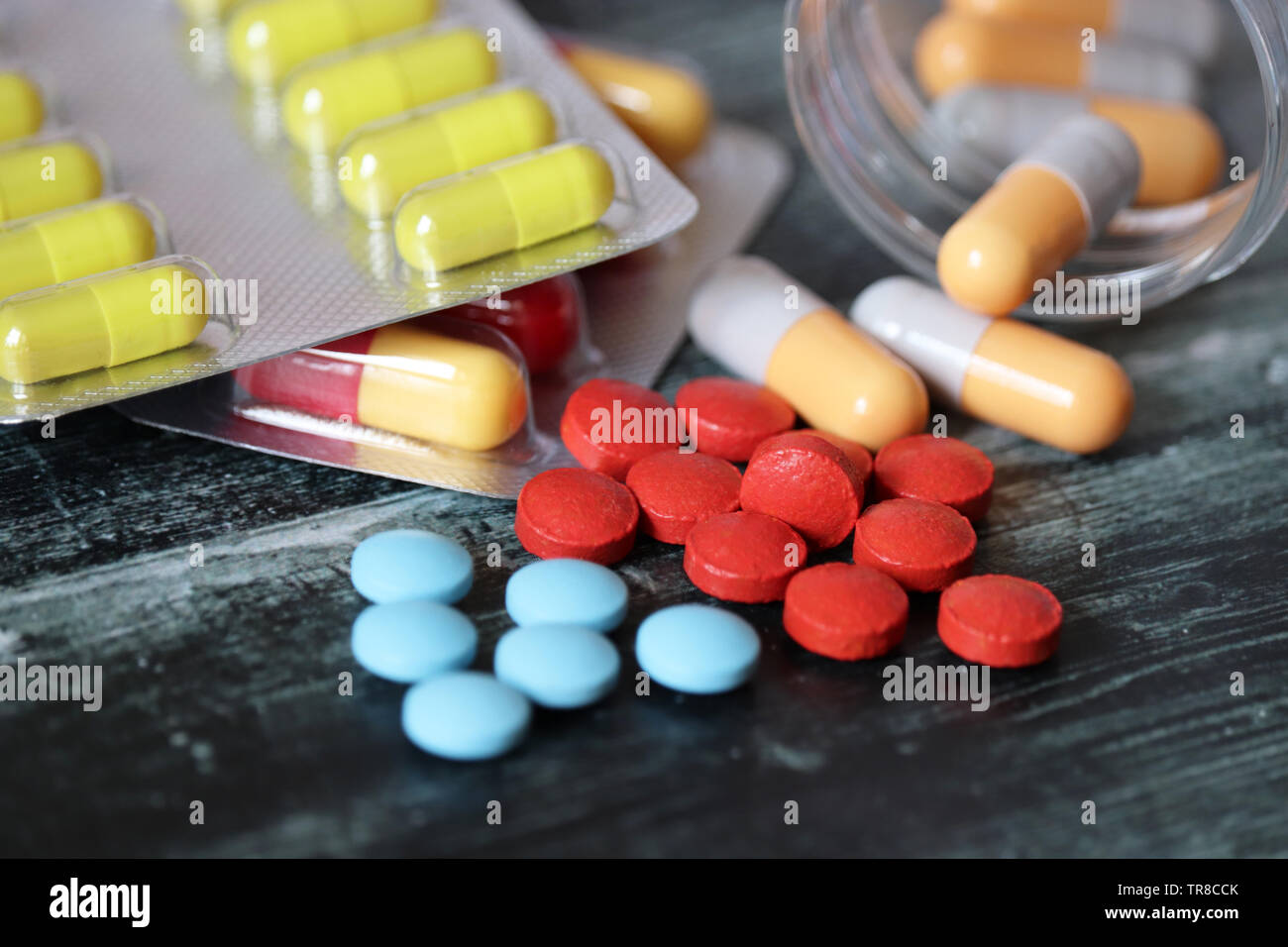 Pillen und Kapseln auf dunklen Holztisch, viele bunte Medikation close-up. Konzept der Apotheke, Vitamine, Gesundheit Stockfoto