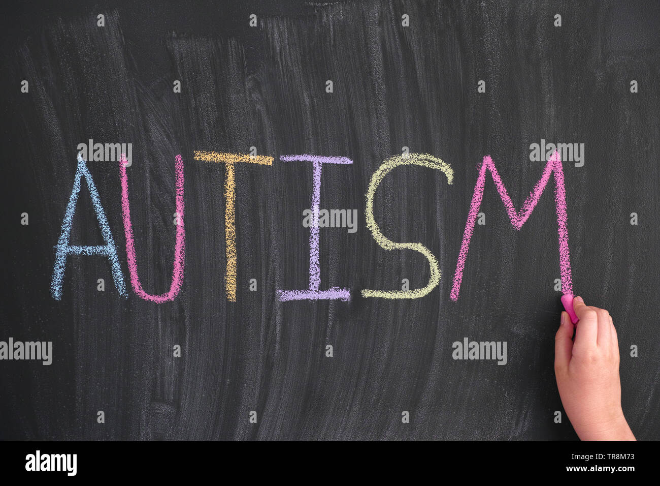 Kind schreiben das Wort Autismus auf einer Tafel. Close Up. Stockfoto