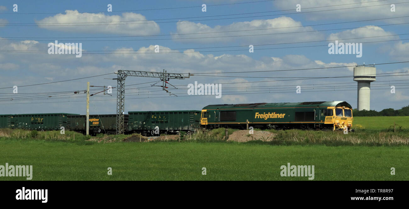 Grüne Freightliner Diesellok 66605 das Forschungslabor Wasserturm in Newton-le-Willows Pass mit einem Stein auf einen sonnigen Frühling Nachmittag. Stockfoto