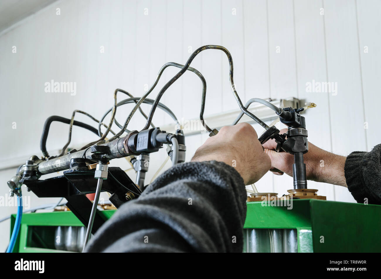 Mechanik reparieren einer Diesel-einspritzdüse. Worker's Hände Einspritzdüse installiert auf einem Prüfstand Maschine. Ein Mann sucht eine Arbeit einer Düse. Stockfoto