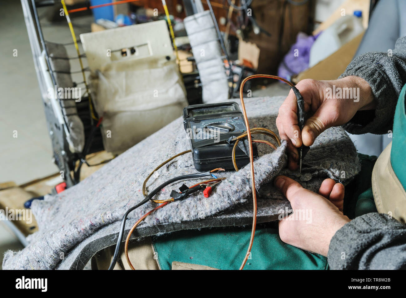 Reparatur von Auto Sitzheizung. Der automechaniker Hände ist mit Multimeter die Spannung am Kabel der Heizung zu prüfen. Stockfoto