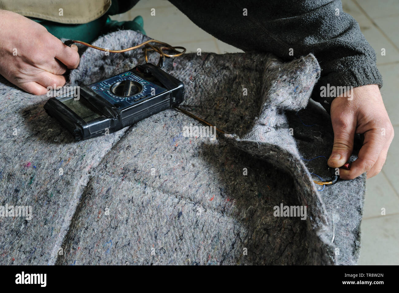 Reparatur von Auto Sitzheizung. Der automechaniker Hände ist mit Multimeter die Spannung am Kabel der Heizung zu prüfen. Stockfoto
