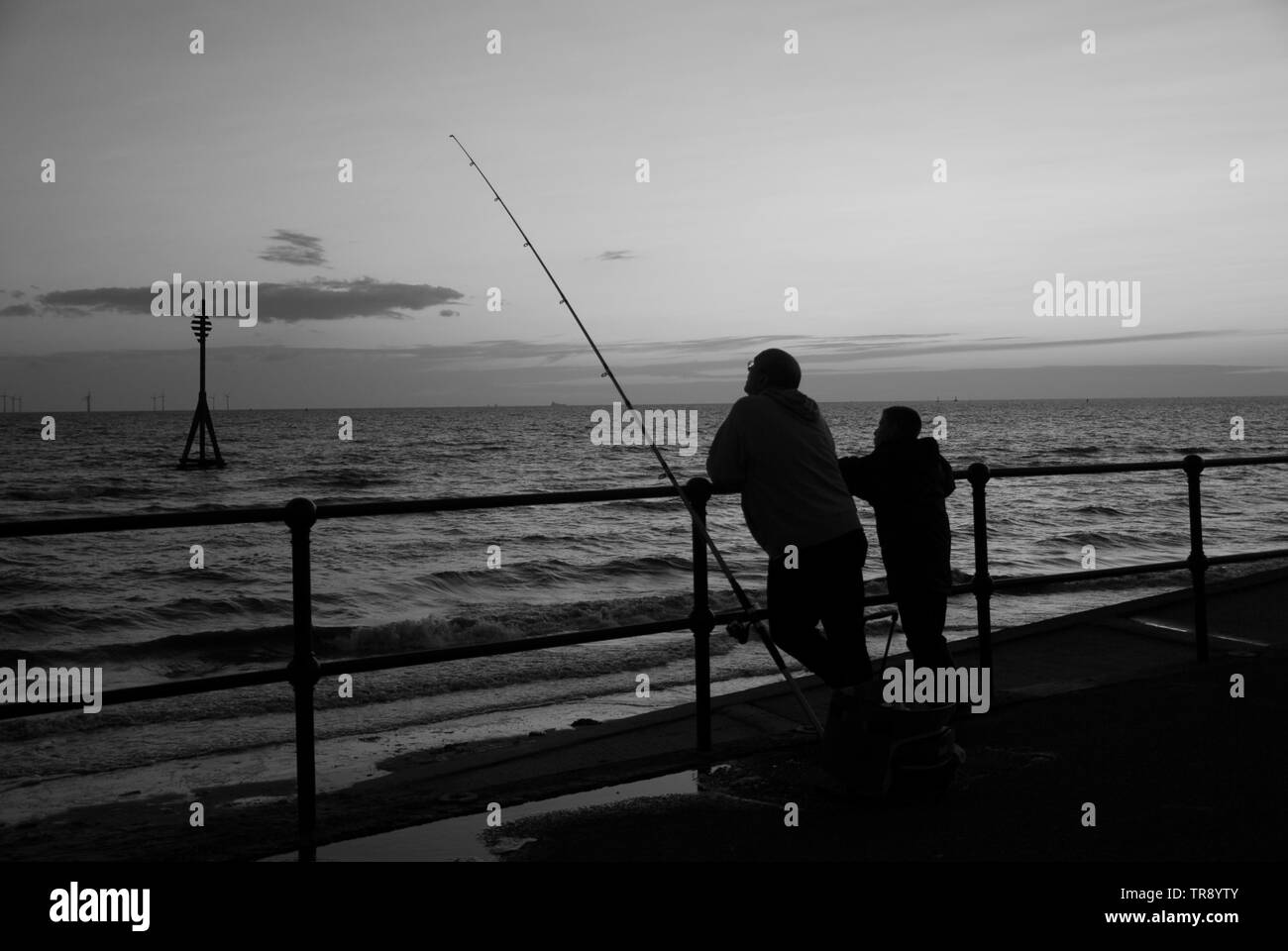 Großvater und Enkel angeln aus dem Meer an der Wand am Crosby beach Liverpool. Stockfoto