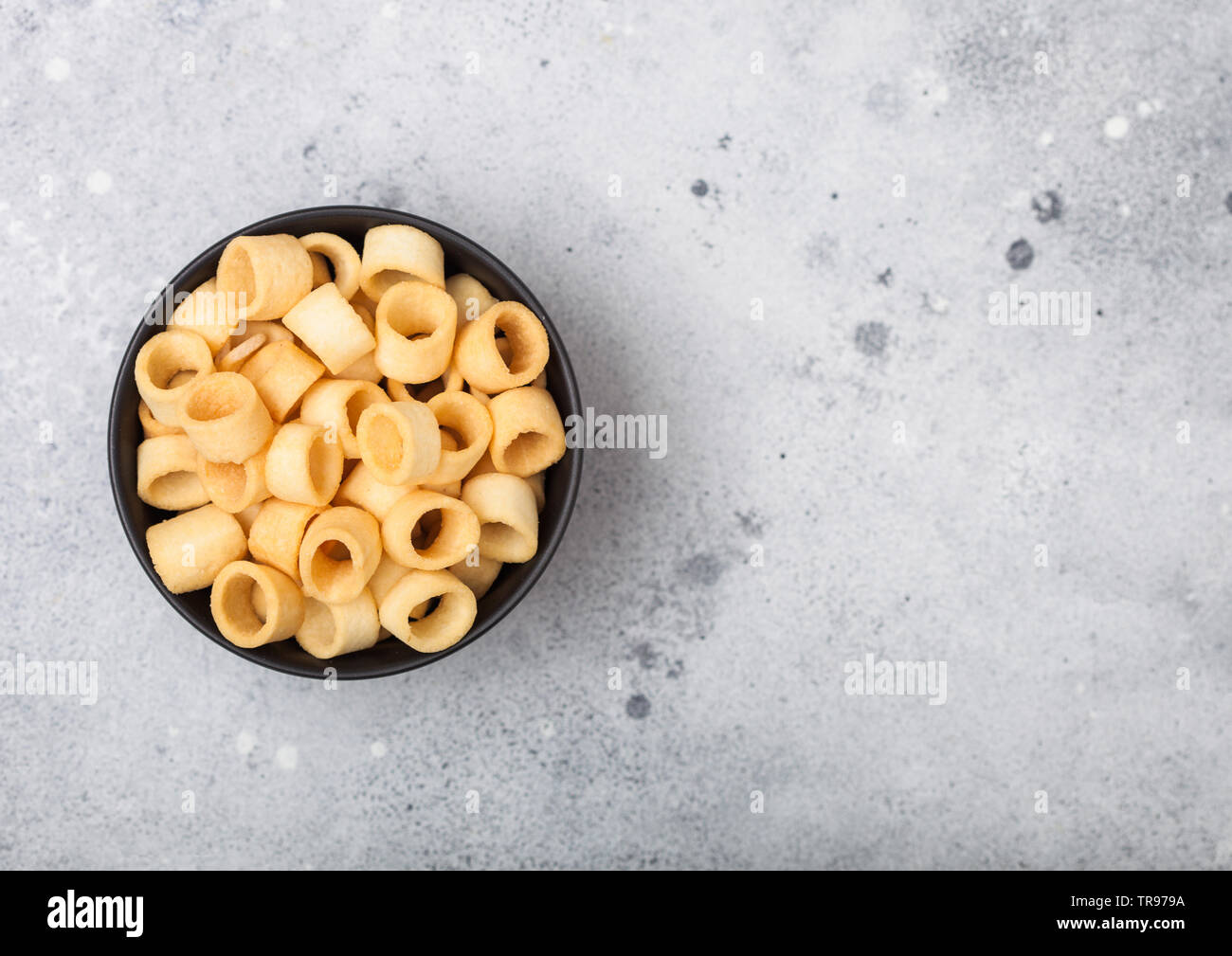 Bereit gesalzen Kartoffel Ringe, die als klassische Snack in schwarz Schüssel auf hellen Hintergrund. Ansicht von oben Stockfoto