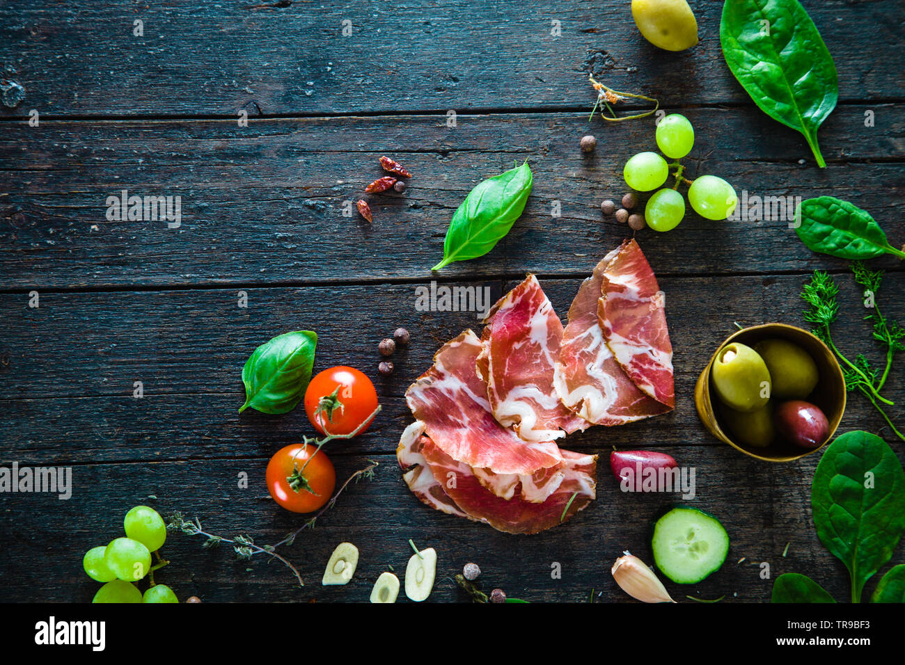 Italienischer Schinken, Prosciutto und Salami. Zutaten für Bruschette, Crostini oder Sandwich Bar. Rustikale Blick von oben auf die Zutaten. Schinken mit Gemüse und spic Stockfoto