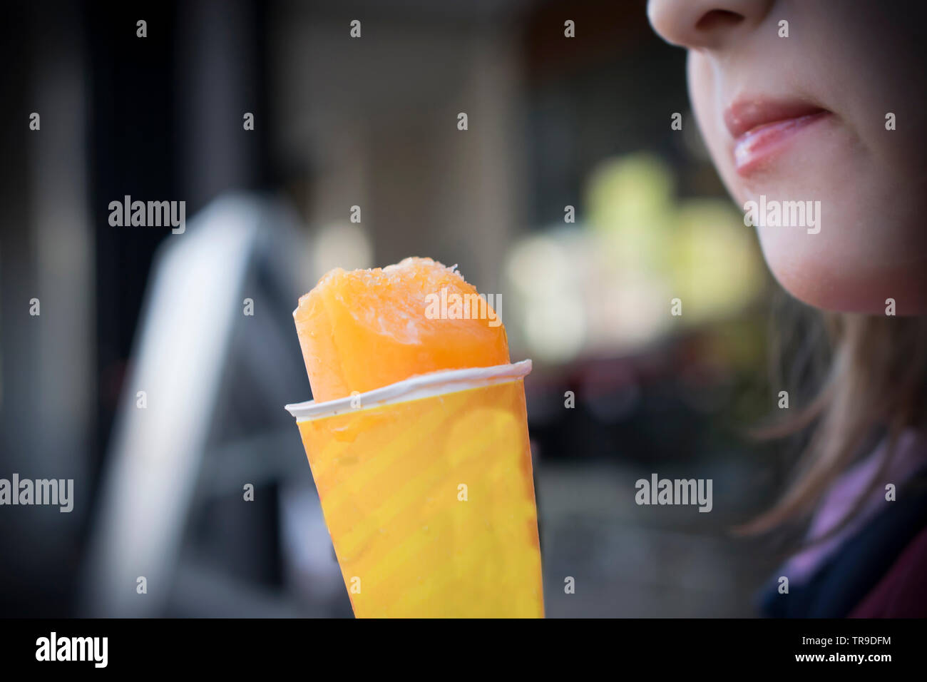 Eine Nahaufnahme von einem Mädchen, das Essen eine orange Eis Stockfoto