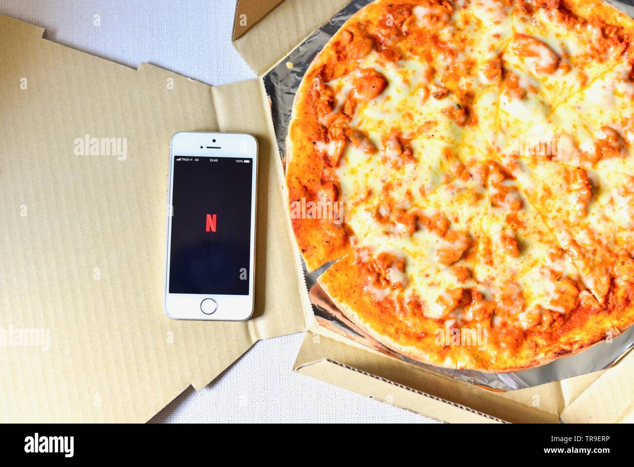 Draufsicht auf das Smartphone mit Netflix Anwendung auf dem Bildschirm und Pizza auf der Seite Stockfoto