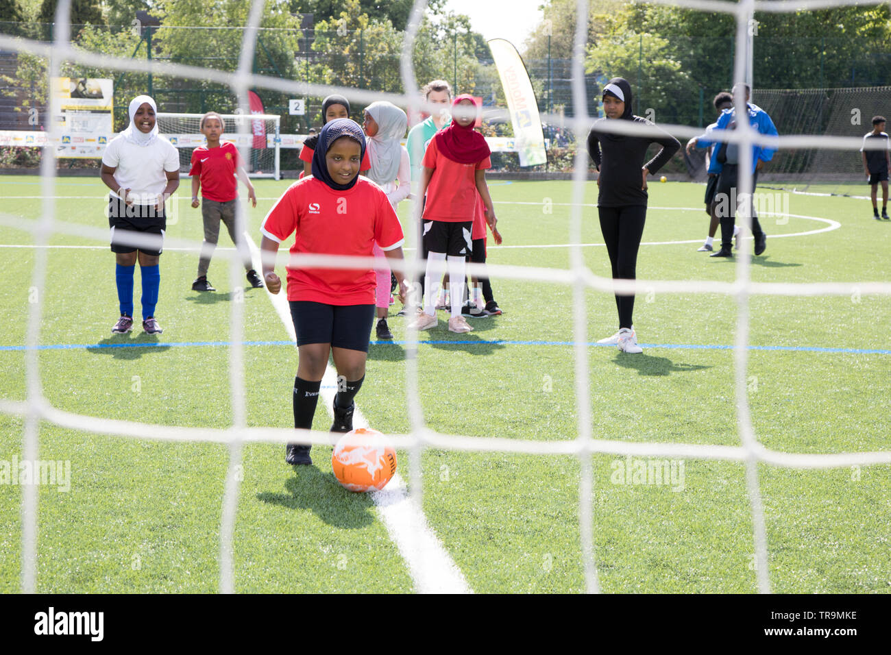 Ein muslimisches Mädchen mit Kopftuch schießt ein Fußball an Ziel während einer Trainingseinheit Stockfoto