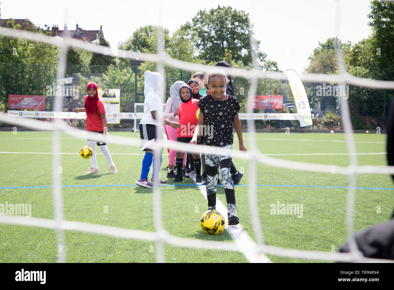 Eine junge schwarze Mädchen nimmt einen Schuß am Ziel während einer Trainingseinheit auf einem Kunstrasen pitch Stockfoto