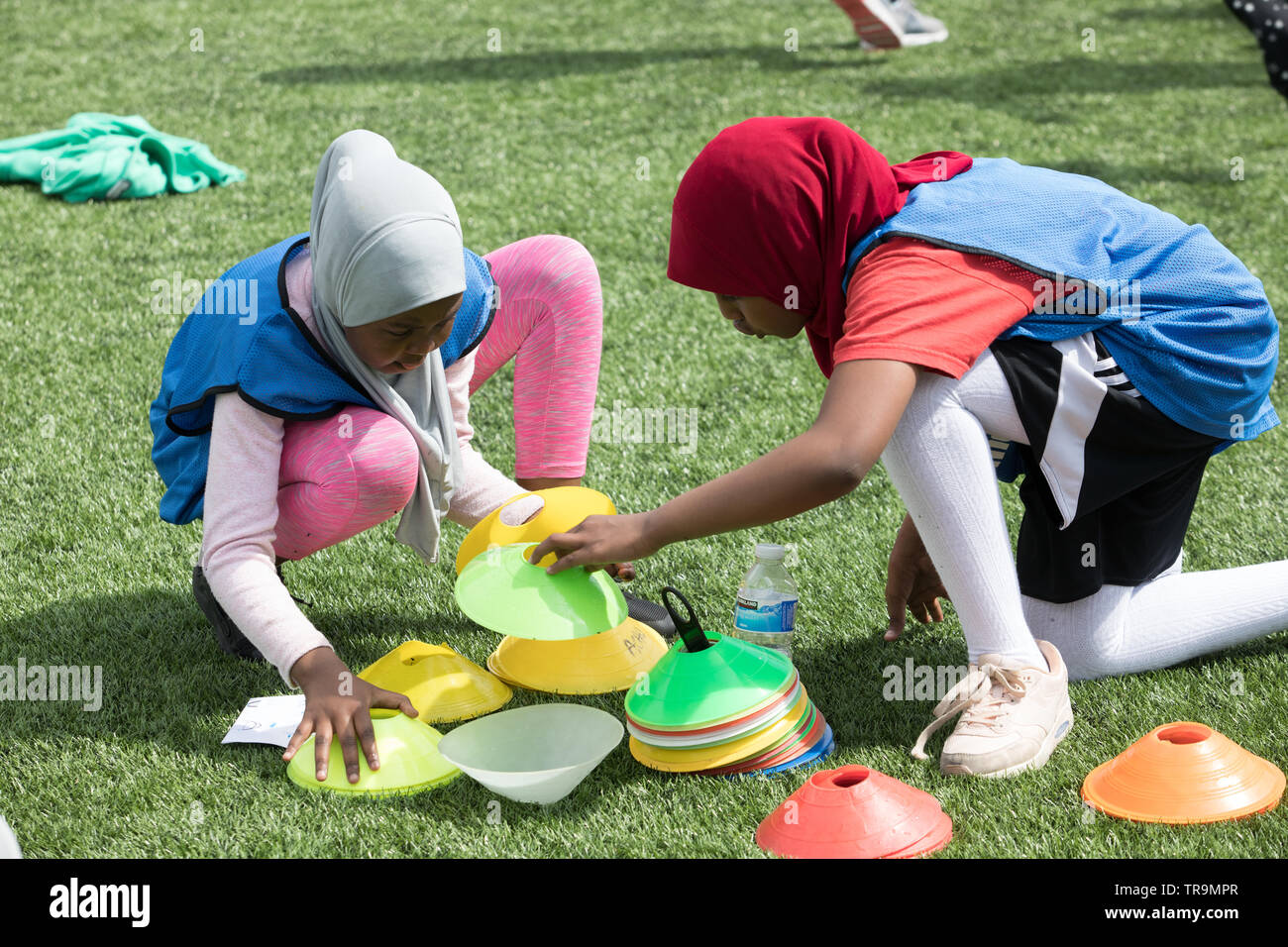 Zwei Mädchen in muslimischen Hijabs Vorbereitung Fußball auf Kunstrasen Ausbildung Pitch mit markierungsteller zu spielen. Stockfoto