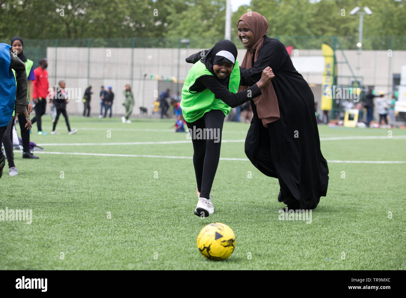 Eine muslimische Mutter Fußball spielen mit Kindern auf einem Kunstrasen Ausbildung Tonhöhe. Stockfoto