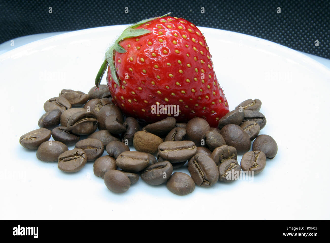Erdbeere und Kaffeebohnen. Erdbeere auf Kaffeebohnen. Stockfoto