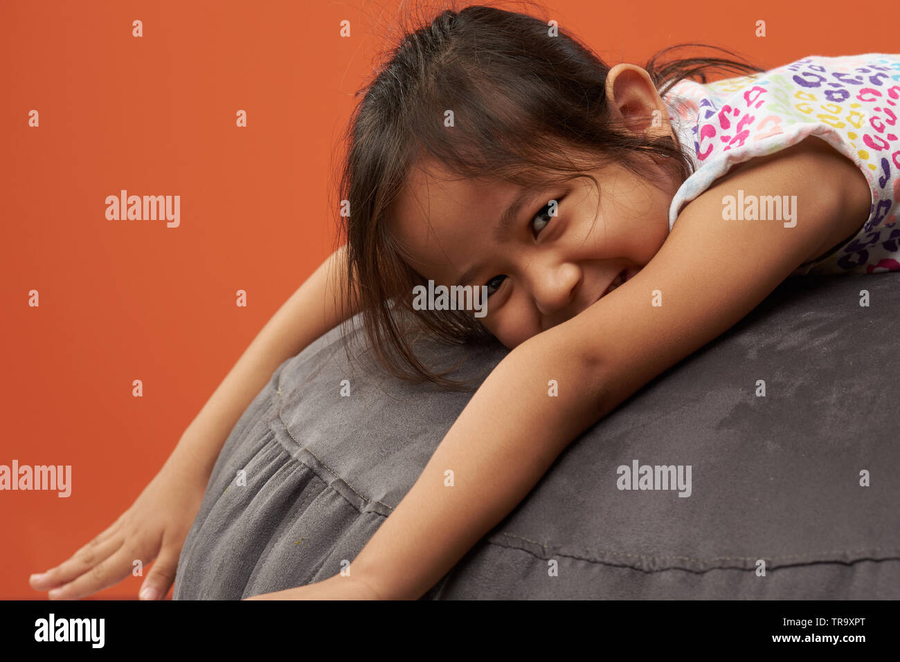Portrait von glücklichen asiatischen kleine Mädchen lag auf weichen Sofa Stockfoto