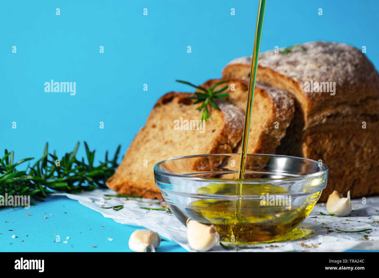 Olivenöl pourin in eine Untertasse Nahaufnahme mit Brot und Kräutern auf bakcground. Mediterrane Küche Konzept. Gesunde Essgewohnheiten. Gvo-frei. Stockfoto