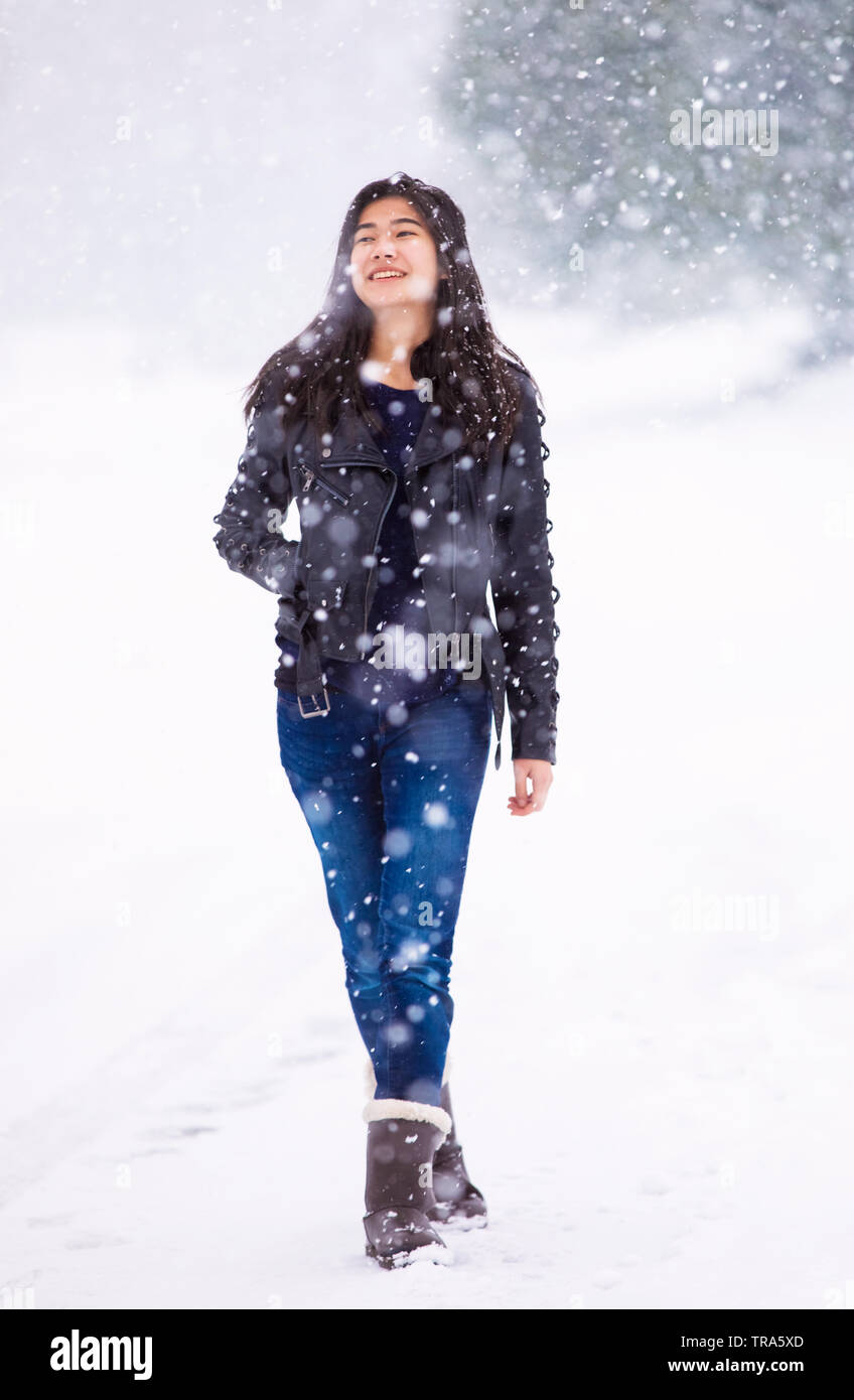 Biracial jugendlich Mädchen tragen schwarze Lederjacke und Jeans hinunter mitten auf der Straße in schweren Schneesturm Stockfoto