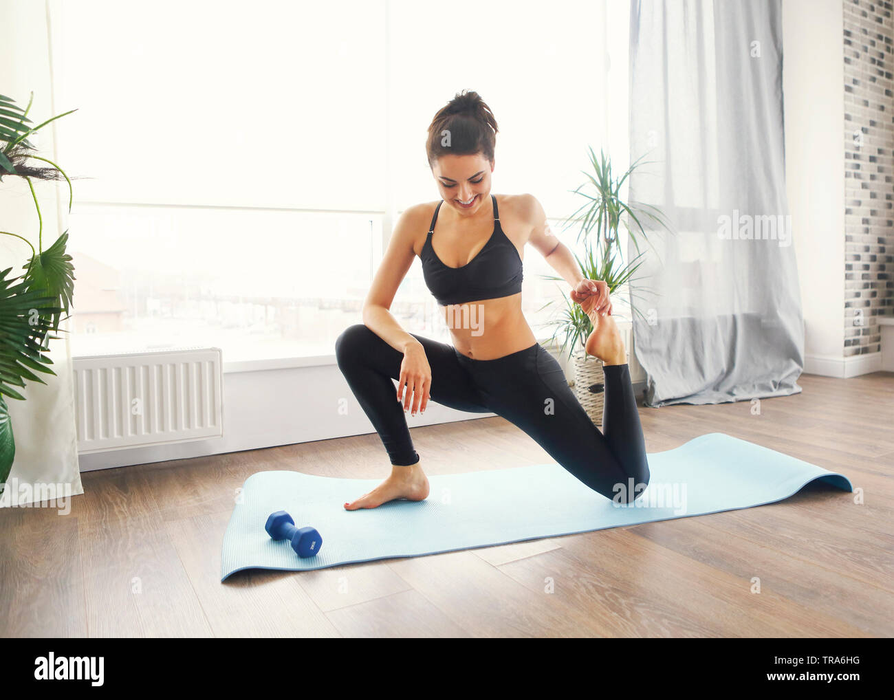 Lächelnde Frau in Sportkleidung Ausübung auf Fitness Matte und Kamera im Wohnzimmer Stockfoto