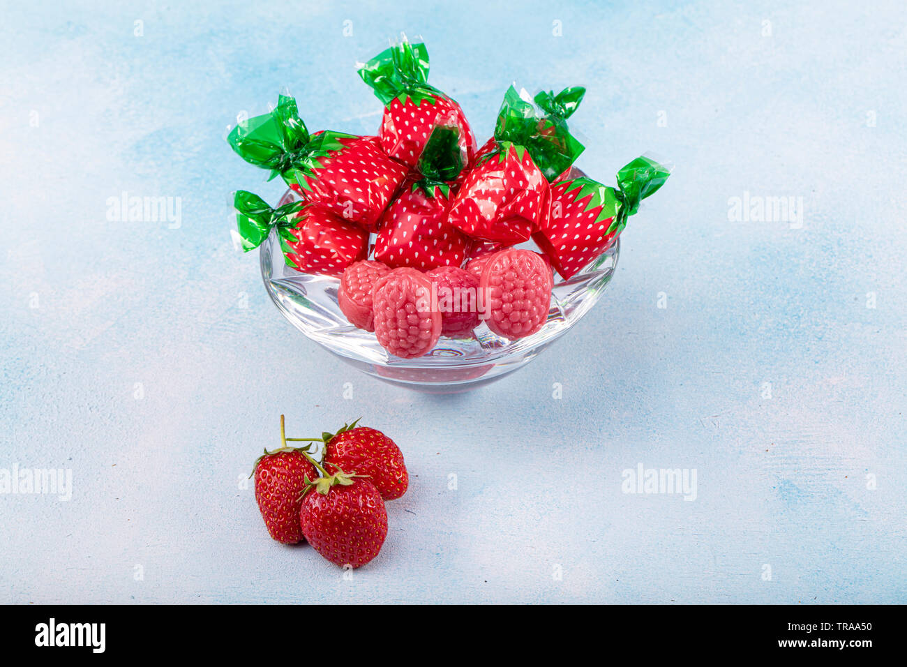 Erdbeere Süßigkeiten und Strawberry flavored candy Konzept mit Nahaufnahme auf süß und sauer Rot sauer Gürtel in Zucker isoliert auf einem hölzernen backgrou abgedeckt Stockfoto