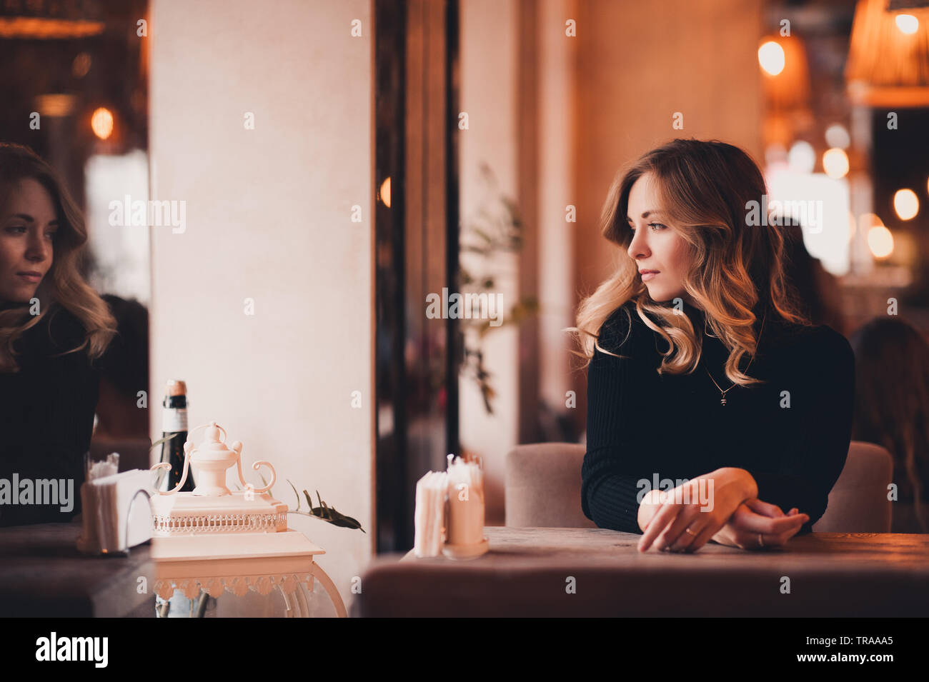 Schöne blonde Mädchen 20-24 Jahre alten im Cafe sitzen mit Blick auf das Fenster. 20. Winter Saison. Stockfoto