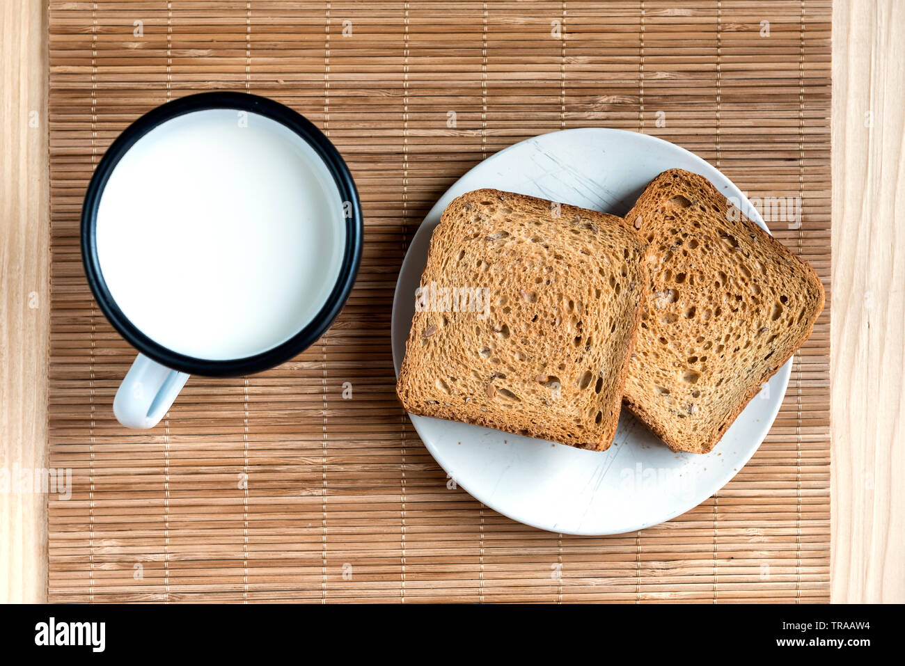 Zwei Scheiben Toast Brot und Zinn Becher Milch auf einem Holztisch, Setup Stockfoto