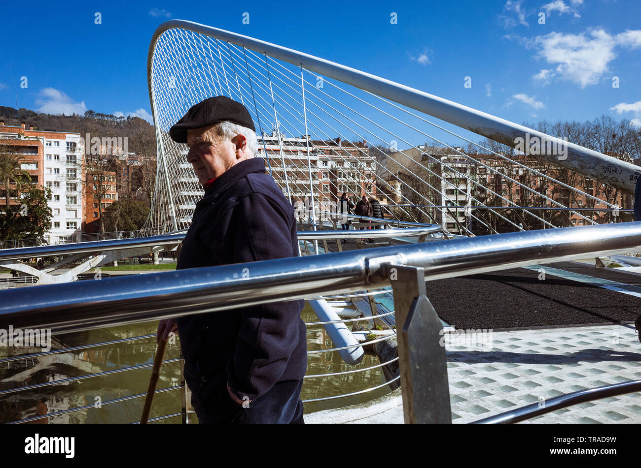 Bilbao, Vizcaya, Baskenland, Spanien: ein älterer Mann an der Zubizuri gebunden Bogen Fußgängerbrücke über den Fluss Nervion, entworfen vom Architekten Santi Stockfoto