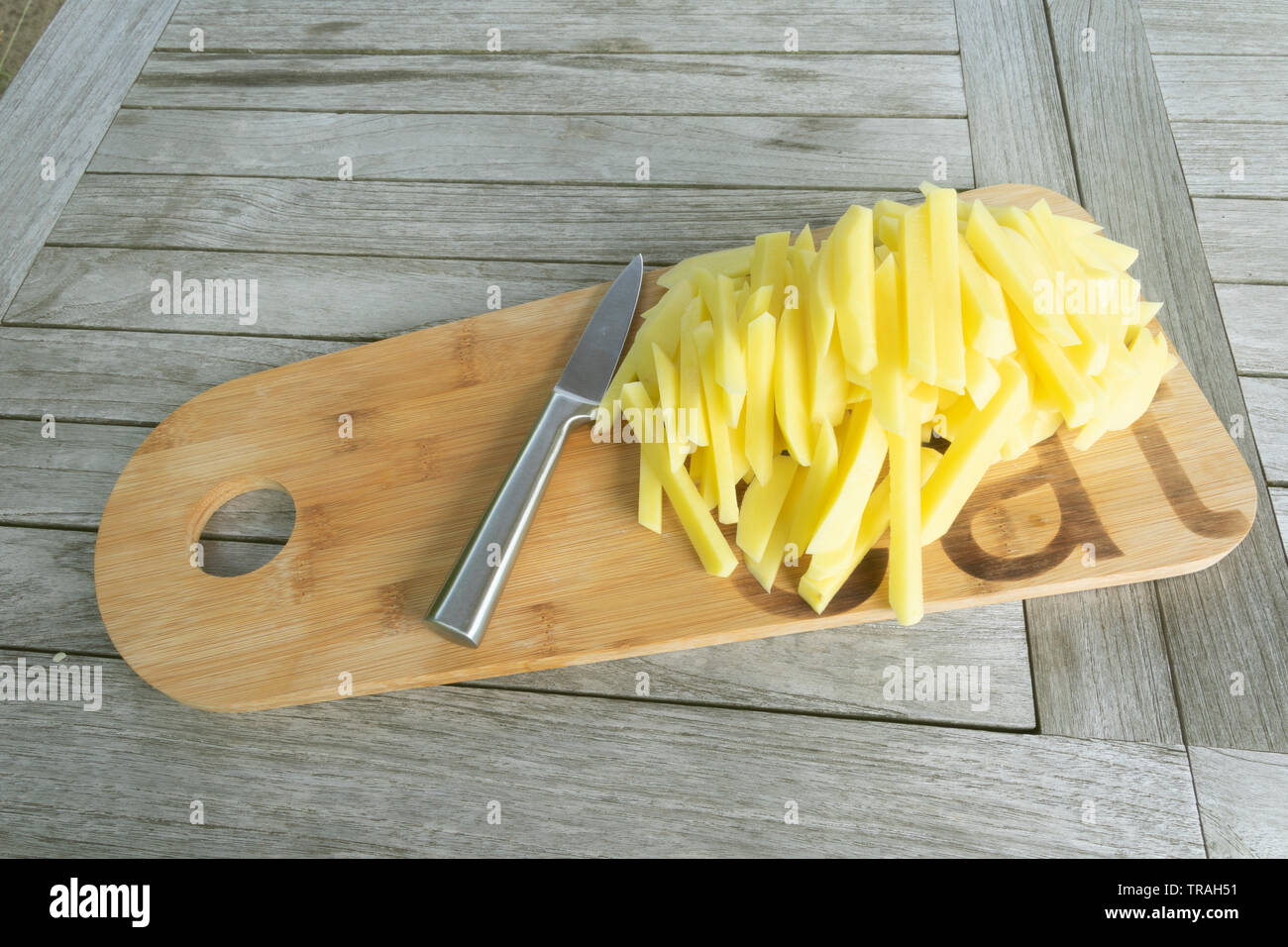 Pommes frites auf einem Holzbrett und einem scharfen Messer schneiden Stockfoto