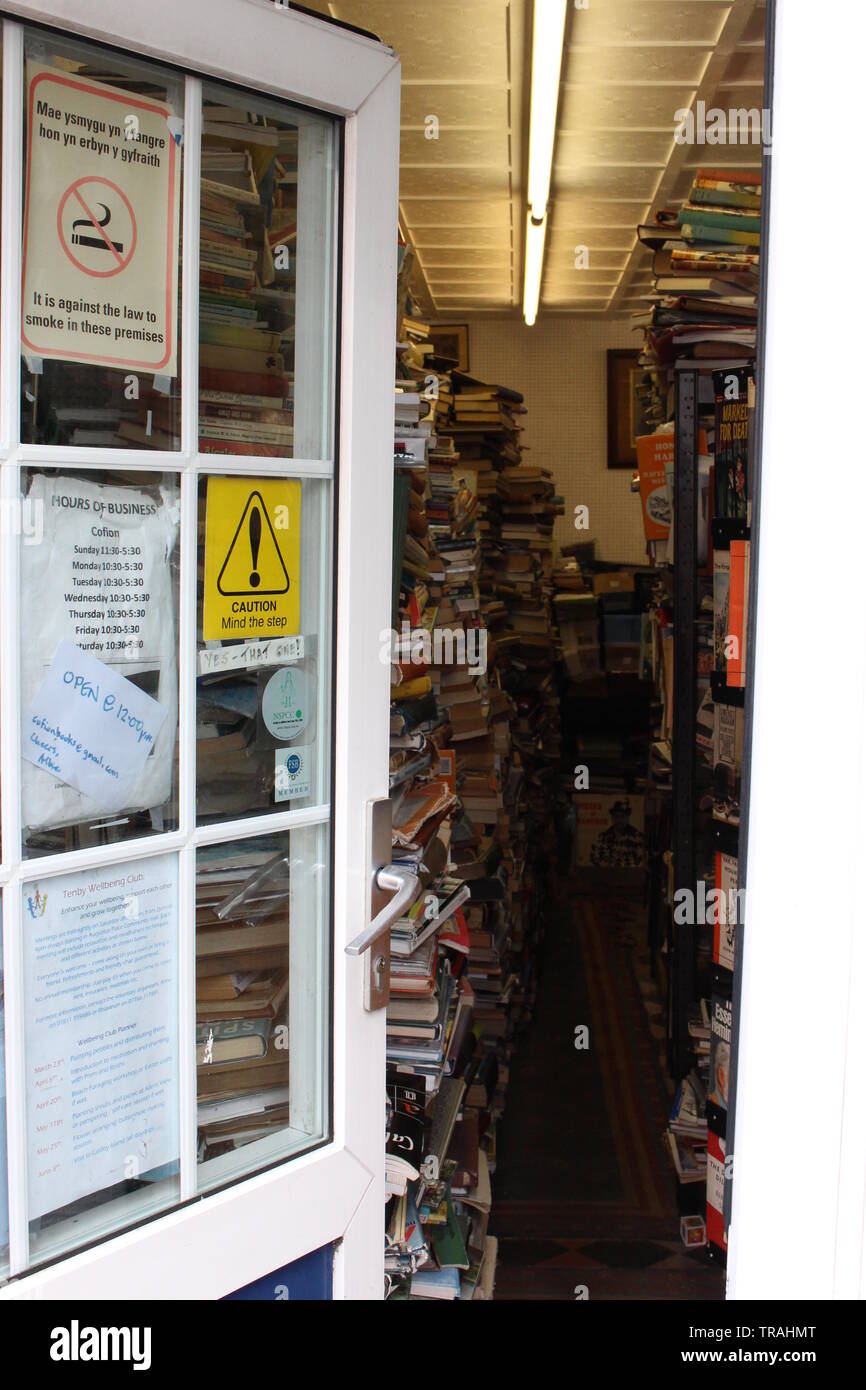 Ein Foto von einer Eingangstür in eine Buchhandlung suchen angehäufte Höhe mit gebrauchten Büchern. Tenby, Pembrokeshire, Wales, Großbritannien Stockfoto