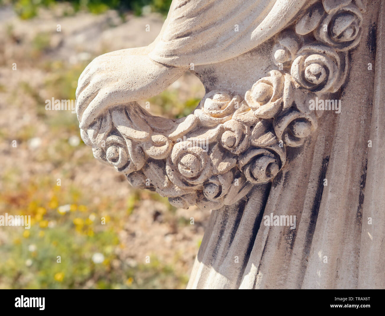 Detail einer weiblichen Statue aus Stein, der Rückseite Links anzeigen, die Hand einer Frau mit einem Kranz aus Rosen, sie fällt leicht über die schwingenden Rock par Stockfoto