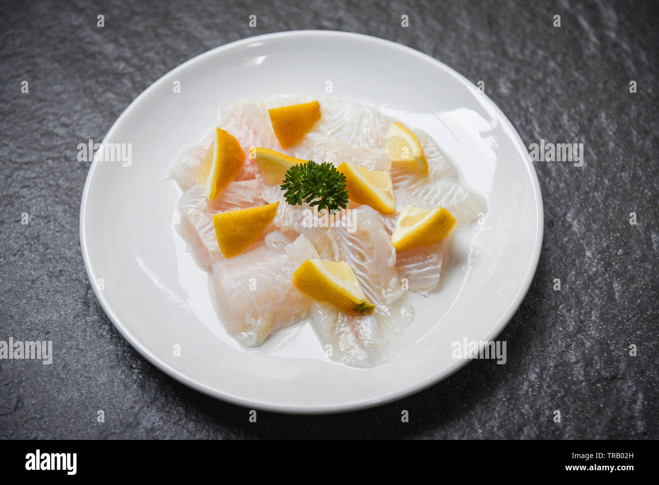 Frisches rohes Fischfilet Stück mit Zitrone auf weiße Platte/Close up Pangasius dolly Fisch Fleisch Stockfoto