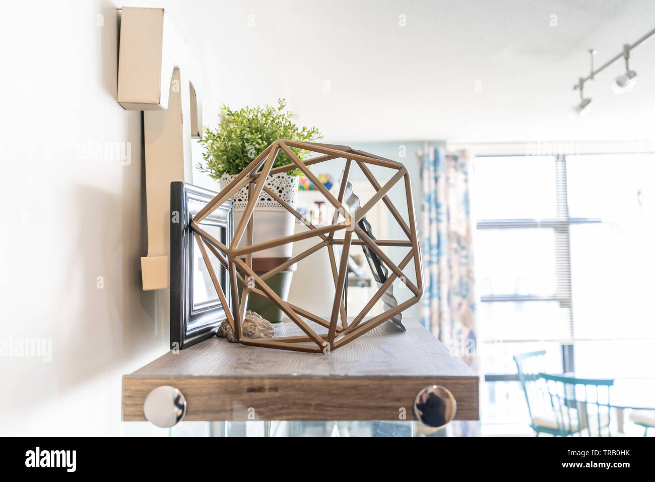 Home Wandregal mit dekorativem Schnickschnack, einschließlich einer geometrischen Kabel Objekt, einen Buchstaben "t", Bilderrahmen und einer Pflanzmaschine. Helles Wohnzimmer Regal. Stockfoto